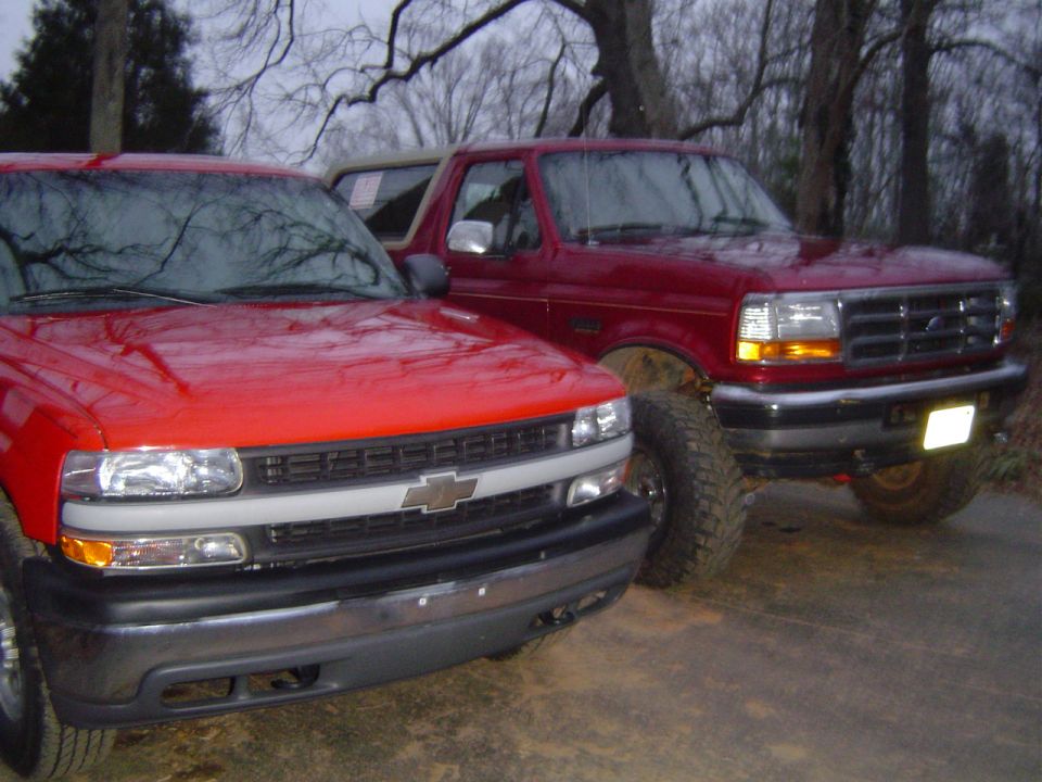 red pickup truck next to a red Ford Bronco