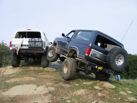 1985 Ford Bronco - Two Ford Broncos tackle a rocky trail, with the blue model in the foreground angled upwards.