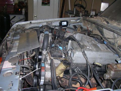 1984 Ford Bronco II - The engine compartment of a vehicle is shown, with various mechanical parts and wiring.