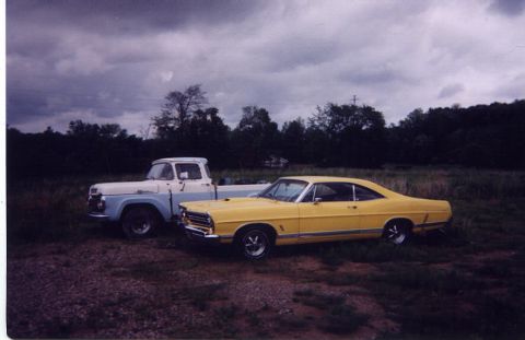 1967 Ford Galaxie - Two classic vehicles, a 1967 Ford Galaxie and a pickup truck, sit parked outdoors on a cloudy day.