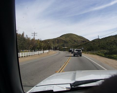 1993 Ford Bronco - Several SUVs are seen driving on a highway with rolling hills under a partly cloudy sky.