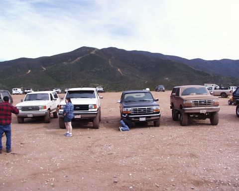 1993 Ford Bronco - Several SUVs are parked in a dusty lot, with a brown 1992 Ford Bronco prominently featured.