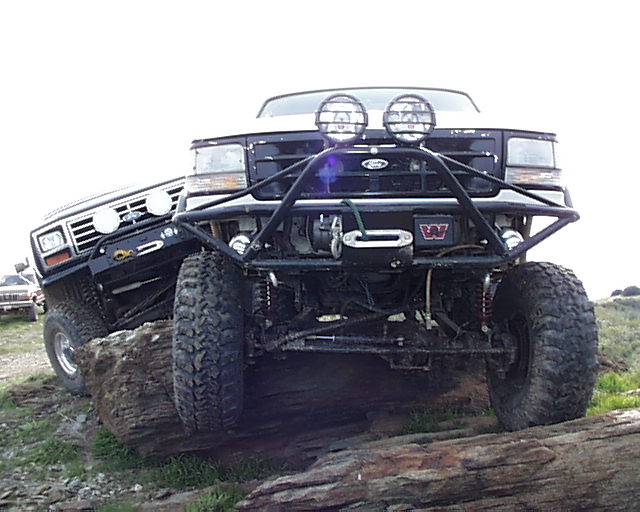 Two Ford Broncos on rocks, one with a winch and lights