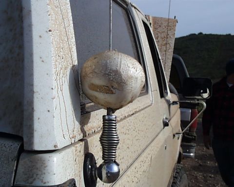 1993 Ford Bronco - A side view of a dirty truck with a unique mirror mount and a person in the background.