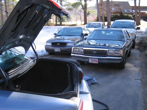 1991 Ford LTD Crown Victoria - A 1991 Ford Crown Victoria is parked in a driveway with other vehicles, its trunk open.