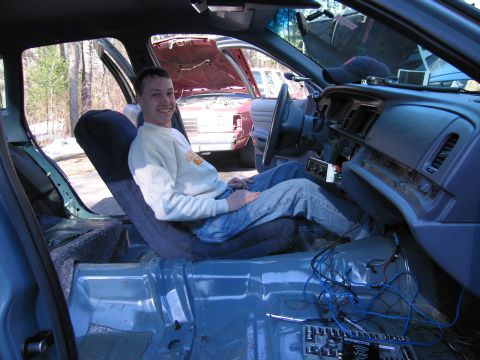 1991 Ford LTD Crown Victoria - The interior of a car is being worked on, with exposed wiring and a person sitting in the driver's seat.