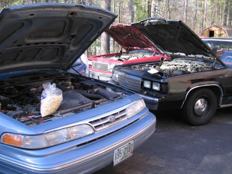 1991 Ford LTD Crown Victoria - Three Ford Crown Victorias, all with hoods open, are parked together in a driveway.