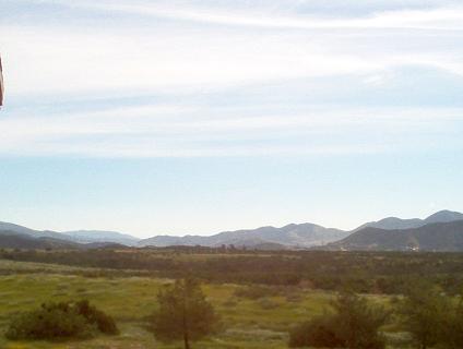 1988 Ford Bronco - A vast expanse of nature unfolds with rolling hills and mountains under a sky dotted with clouds.
