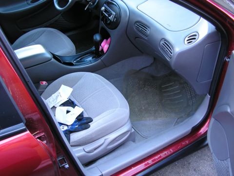 1998 Ford Taurus - The interior of a 1998 Ford Taurus, the passenger seat with gloves and a receipt on it, and the dashboard.