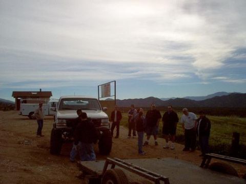 1988 Ford Bronco - A group of people gather around a white Ford F-Series truck in an outdoor setting with mountains in the background.