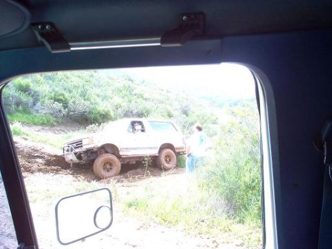 1988 Ford Bronco - A white 1988 Ford Bronco navigates a muddy trail in a rural landscape.