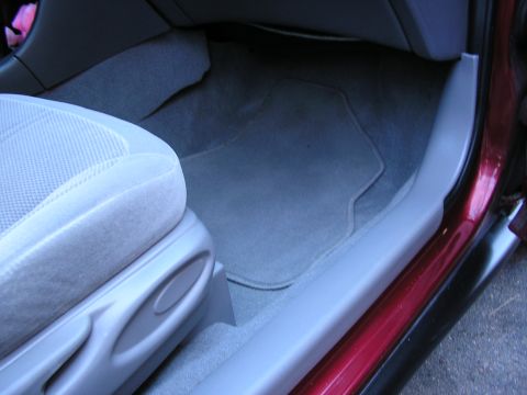 1998 Ford Taurus - The interior of a car shows the passenger seat base and the floor mat.