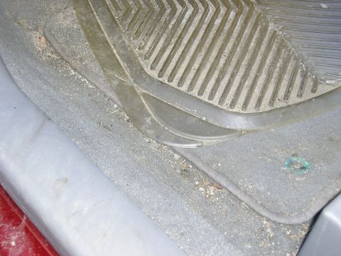 1998 Ford Taurus - The interior of a vehicle shows a worn floor mat covered in dust and dirt.