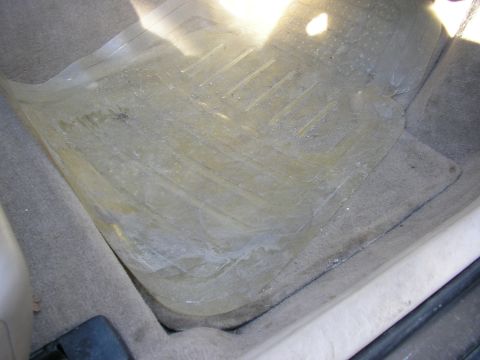 1998 Ford Taurus - The interior floor mat of a car shows signs of wear and tear, with dirt and water stains visible.
