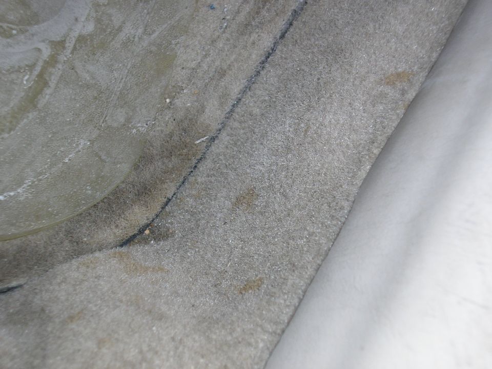 Interior carpet detail with a black seam and brown stains