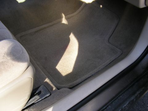 1998 Ford Taurus - Tan carpeted floor mats are visible in the driver's side interior of a car.