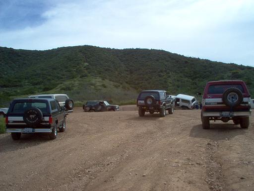 Black Ford Bronco rear view, spare tire on back, aftermarket wheels, dirt road