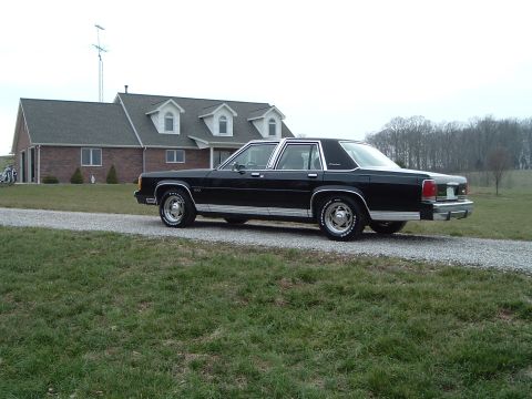 1989 Ford Crown Victoria LTD - A black 1989 Ford Crown Victoria LTD is parked on a gravel driveway in front of a large brick house.