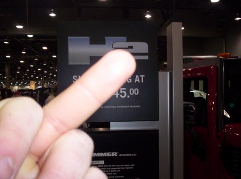 1989 Ford Bronco - Signage for a HUMMER H2 at an auto show, with a red vehicle visible.