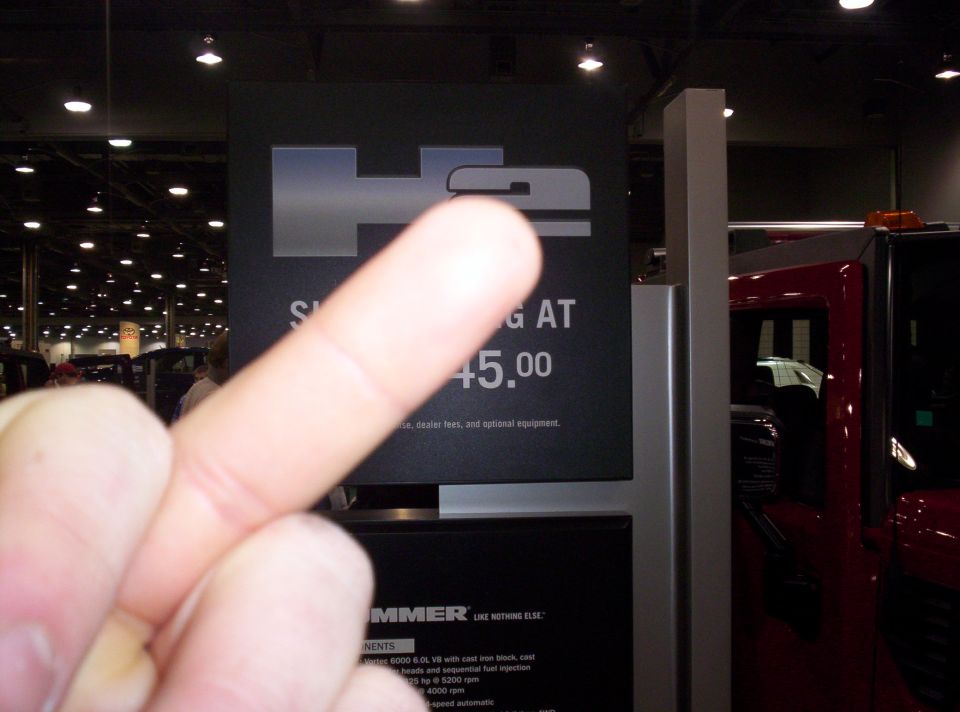 HUMMER H2 sign with price, red vehicle in background