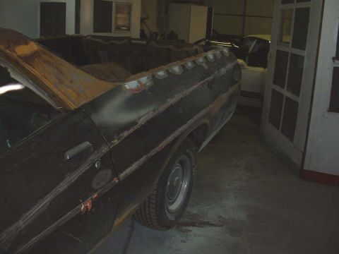 1972 Ford Ranchero - The rear section of a vehicle, showing rust and unfinished bodywork, sits in a garage.