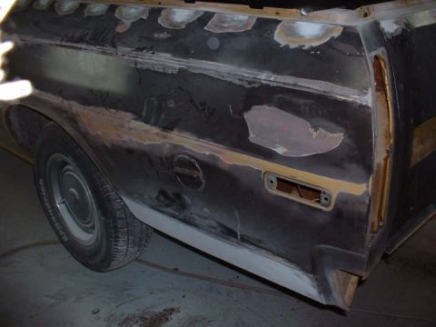 1972 Ford Ranchero - The side of a 1972 Ford Ranchero is undergoing bodywork, revealing primer and filler in various patches.