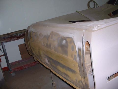 1972 Ford Ranchero - The side panel of a 1972 Ford Ranchero is undergoing bodywork, revealing areas of rust and damage beneath the primer.