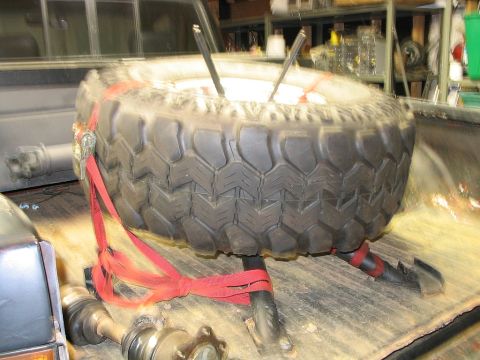1986 Ford F-150 - Spare tire and drive shafts are strapped down in the bed of a pickup truck.