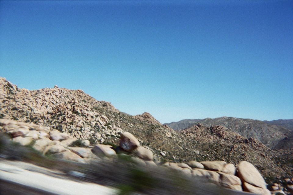 Rocky desert ridge and distant mountains under blue sky, motion-blurred foreground