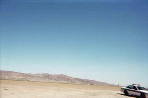 1990 Ford Bronco - light-colored car sits at the edge of a vast flat desert plain backed by low distant mountains.