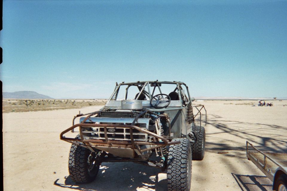 Front view of a tube-chassis off-road race buggy parked on desert hardpan