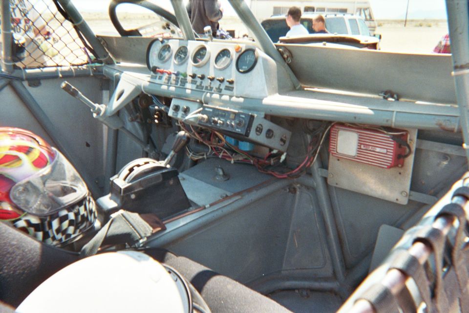 Interior of a tube-frame race vehicle showing dashboard gauges, switches and wiring