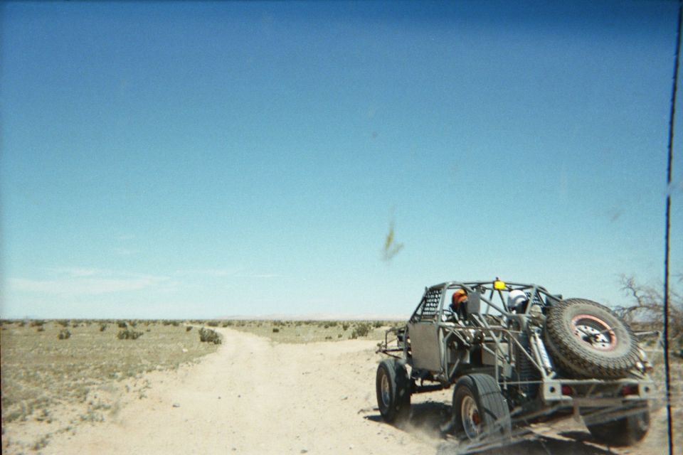 Off-road buggy on a trailer being towed down a desert dirt road