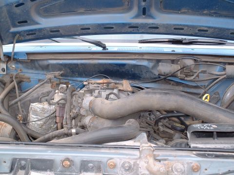 1990 Ford Bronco - The engine bay of a vehicle is shown, with visible hoses and engine components. Text on a part indicates a date of 12/92.