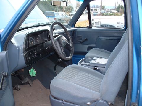 1990 Ford Bronco - The interior of a 1990 Ford Bronco shows grey cloth seats and a dashboard with a prominent steering wheel.