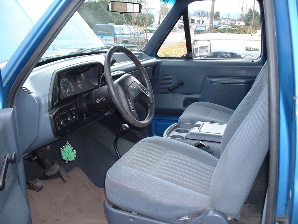 Blue Ford Bronco interior with grey cloth seats, dashboard, steering wheel, and center console. A 'Supermotors.net' watermark is visible