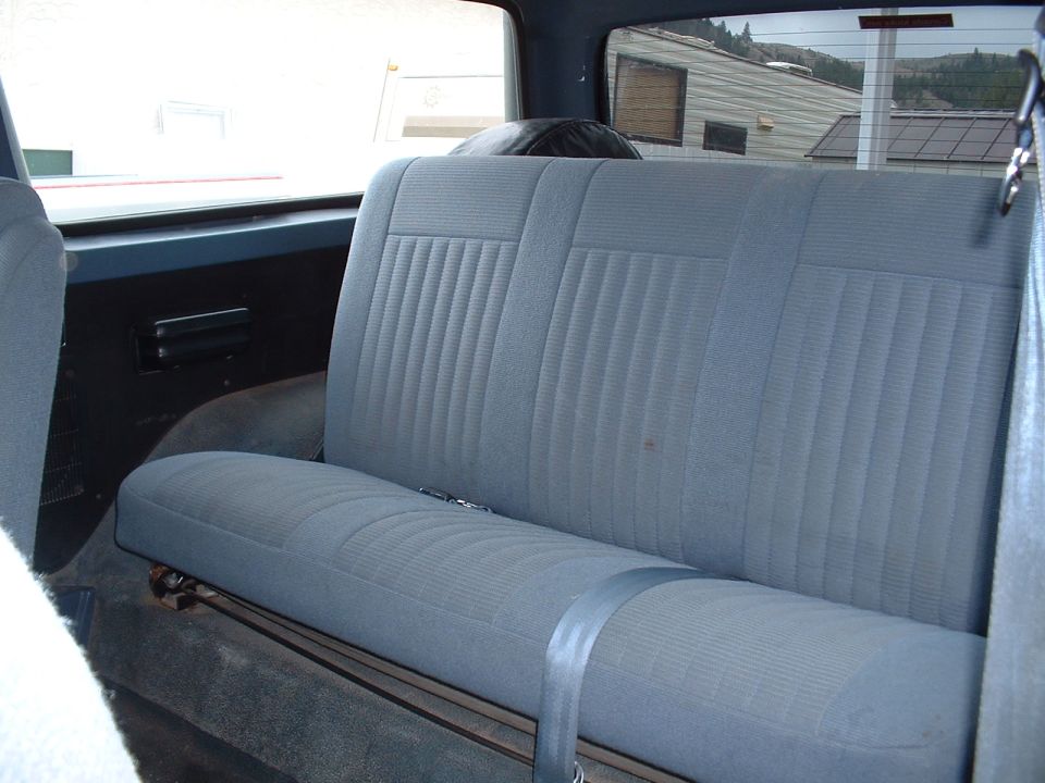 Interior rear seat of a vehicle with blue fabric upholstery and a seatbelt