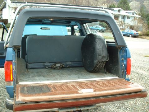 1990 Ford Bronco - Rear view of a 1990 Ford Bronco with the tailgate down, revealing the interior cargo area.