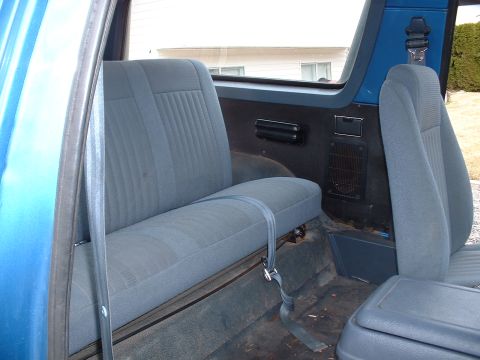 1990 Ford Bronco - Interior view of a blue SUV, showing the rear bench seat and part of the front passenger seat.