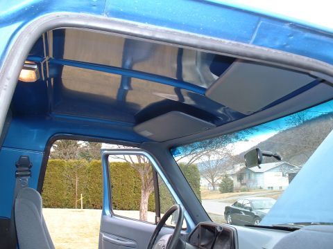1990 Ford Bronco - Interior view of a blue truck, showing the dashboard and the open passenger door revealing the exterior.