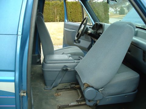1990 Ford Bronco - The interior of a blue SUV, likely a 1990 Ford Bronco, shows cloth seats and a center console.