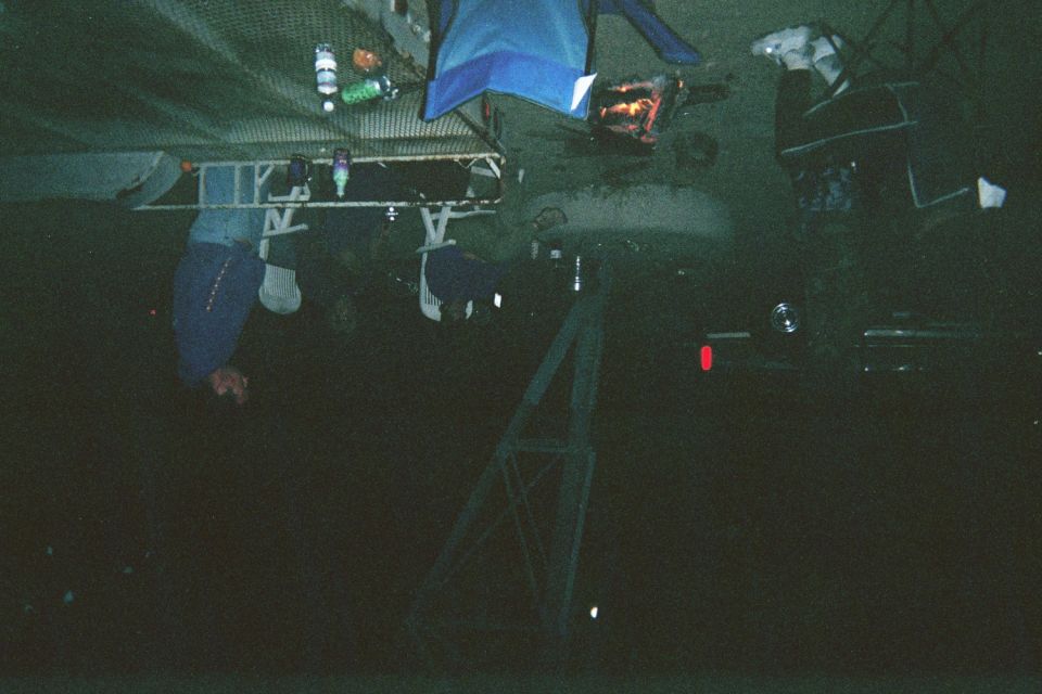 Dark blurry nighttime scene at a desert camp with a fire and indistinct figures