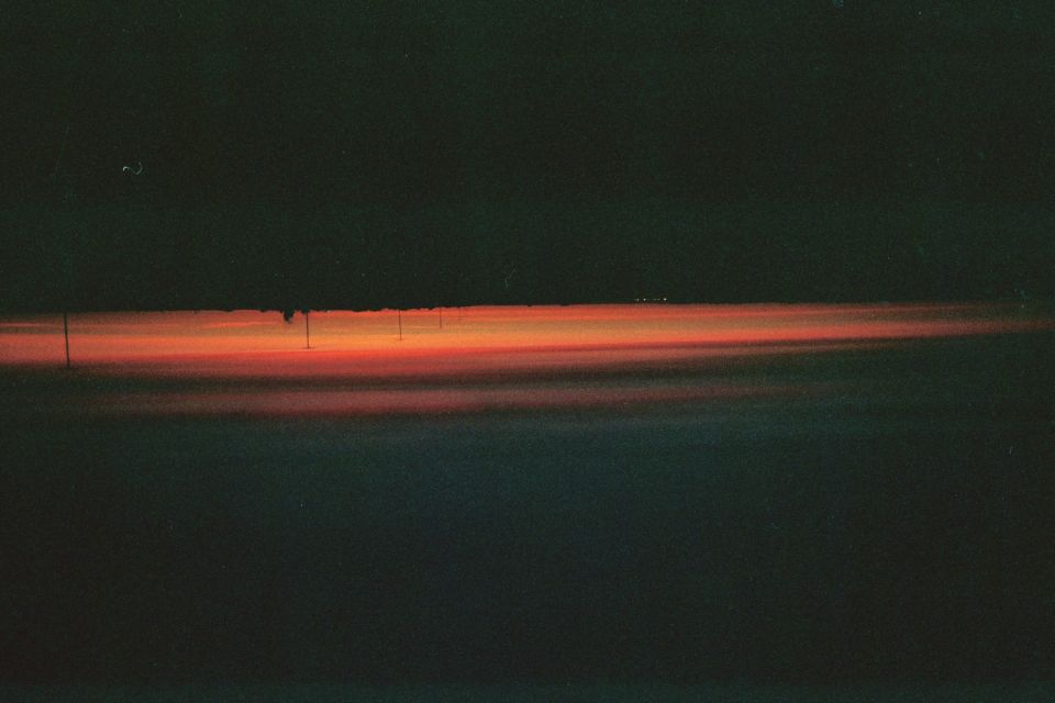 Distant orange sunset glow along the horizon over a dark desert landscape