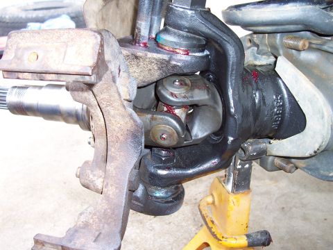 1994 Ford F-150 - Close-up view of the front axle and suspension assembly, showing the universal joint and ball joints, with visible grease and a part number.