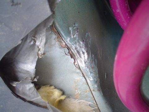 1993 Ford Taurus - Close-up of damage and rust on the interior of a vehicle, with a bright pink object visible.