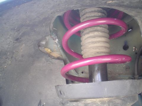 1993 Ford Taurus - A damaged fender liner is visible around the suspension strut and purple spring.