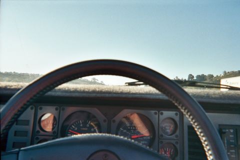 1990 Ford Bronco - From the driver's seat, a sport steering wheel frames a dashboard with twin tachometer and speedometer gauges and a sunlit landscape beyond.