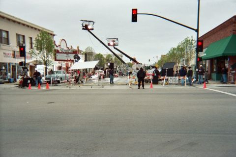 1990 Ford Bronco - film set spans a closed downtown intersection with two camera cranes, crew, traffic signals and Road Closed barriers in the distance.