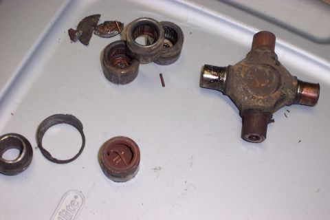 1990 Ford Bronco - Disassembled U-joint and bearing cups are laid out on a gray surface.