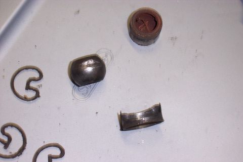1990 Ford Bronco - U-joint bearing cap, roller bearings, and a small container of grease are laid out on a surface.